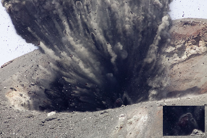 Beginning of a more powerful explosion. The plug on the conduit is thrown out and rocks separate in a fan shape spray. In the deep inside, a weak glow can be seen at some blocks. (Photo: Tom Pfeiffer)