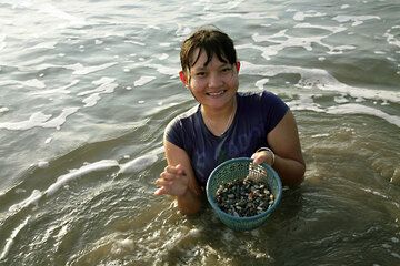 Girl collecting edible shells in the beach sand (Photo: Tom Pfeiffer)