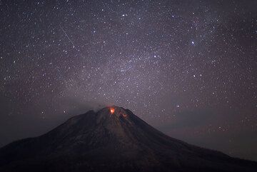 A meteor passes above Sinabung volcano with its two active lava lobes. (Photo: Tom Pfeiffer)