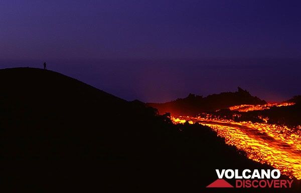 Night-time lava flow on Etna volcano. A photographer stands on the rim to the left. (Photo: Tom Pfeiffer)