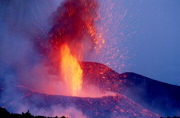 Blau und rot, und alle Sinne auf Hochtouren, als man da war. Während die flüssigen Fetzen einer Explosion noch fast zusammenhängend aus dem Krater schießen, steigt eine neue glühende Feuersäule aus dem Krater hervor. (Photo: Tom Pfeiffer)