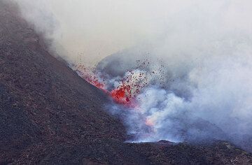 A small fountain of liquid lava appears at the lower end of the fissure feeding the lava flow. (Photo: Tom Pfeiffer)