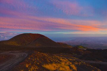 The setting sun paints the clouds in the sky, while the Monti Silvestri and, far behind and below, Catania and the Ionian Coast of Sicily, are already in the evening shadow. (Photo: Tom Pfeiffer)