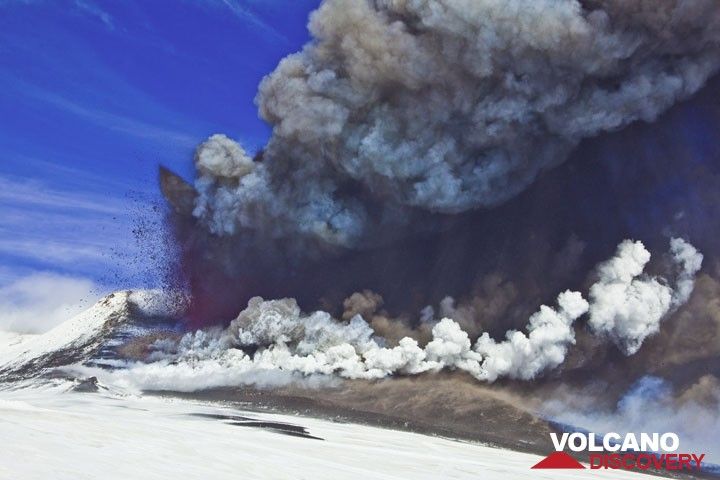 The lava fountain is now well over 300 m high and the ash plume rises several km. The lava flow from the saddle vent meets fresh snow and produces a white steam plume at the base of the cone. (Photo: Tom Pfeiffer)