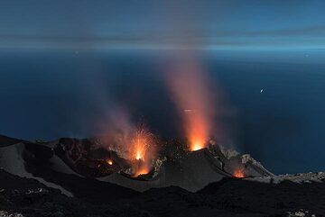 Moonlight illuminates the crater terrace (9 June 2017 night); a rare eruption occurs from the northern central vent (the only one observed during many hours). (Photo: Tom Pfeiffer)