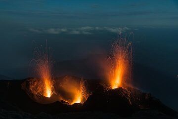 Dreifacher Ausbruch aus den westlichen, zentralen und östlichen Quellen des Vulkans Stromboli. Im Hintergrund ist der Mondlichtschatten der Insel über dem Meer zu sehen. (Photo: Tom Pfeiffer)