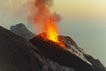 Der gleiche Ausbruch, der eine halbe Minute dauerte, wurde aus einem größeren Winkel aufgenommen, so dass der nordwestliche Hornitokegel sichtbar ist. Die kegelförmige Vulkaninsel Filicudi im staubigen Hintergrund des Sonnenuntergangs. (Photo: Tom Pfeiffer)