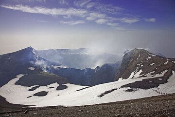 La vue depuis le sommet sur le complexe cratère central, composé du Voragine et Bocca Nuova (fond). Le groupe donne l'échelle. (c)