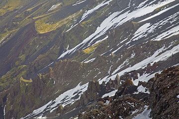 Patches of snow on ash-covered slopes between eroded dykes on the wall of Valle del Bove. (c)