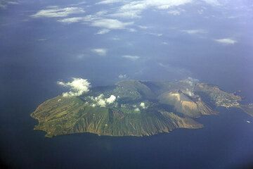 Blick vom Flugzeug auf Vulcano: deutlich erkennt man den älteren Teil der Insel (links), der ein von einer Kaldera abgeschnittener Stratovulkan ist und die jüngere Kaldera rechts, inder der moderne Hafen und das Dorf neben dem aktiven, jungen Vulkankegel La Fossa (hellbraun) liegen. Eine schmale Landzunge verbindet den Hautpteil der Insel mit der Halbinsel, die der in der Antike entstandene kleine Kegel Vulcanello bildet (zum größten Teil außerhalb des Bilds rechts).   (Photo: Tom Pfeiffer)