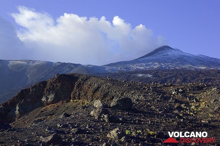 We're on the NE rift zone; to our left, a pit crater, a few hundred meters upslope the still smoking upper part of the Oct 2002 eruptive fissure, the Pizzi Deneri and Northeast crater in the background. (Photo: Tom Pfeiffer)