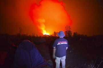 Myself wearing the VolcanoDiscovery T-Shirt for a night-time photo from the camp. (Photo: Tom Pfeiffer)