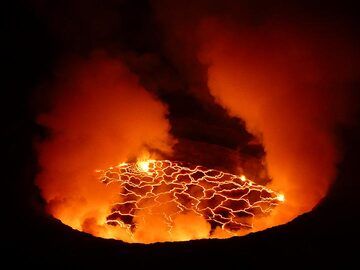 A selection of photographs taken by Ingrid Smet during our June 2017 Nyiragongo lava lake and mountain gorillas expedition in the DR Congo which included a 3 days / nights stay on Nyiragongo volcano. 
On 6 June the group completed their hike to the summit in dry weather (the people coming up in the next two days were not so lucky) but  had to wait a few hours for a first glance onto the red hot lava lake until the clouds around the stratovolcano´s summit and the thick volcanic gasses inside the caldera had temporarily lifted. The next 2 days (7 and 8 June) visibility into the caldera was usually best in the mornings and at intervals during the night, with more clear circumstances in the early morning and right through to dawn and sunrise on the 8th of June. The world´s largest lava lake (about 220 m across) is situated some 400 m below the rim of Nyiragongo´s summit caldera (a diameter of 1.2 km). When visible, the surface of the active lava lake was continuously in motion as exploding gas bubbles create small degassing fountains that recycle the cold black crust back into the red hot liquid lava. Strong degassing also occurred from the edges of the lava lake, the 2016 hornito and along the southern fracture zone.  (Photo: Ingrid Smet)