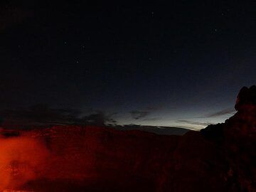 The lava lake´s red glow illuminates the steep  inner walls of Nyiragongo´s summit caldera whilst the sky to the east shows both the nightly stars and first morning light. (Photo: Ingrid Smet)