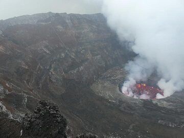 Blick auf den aktiven Lavasee und die westlichen inneren Calderawände. Die mehr oder weniger horizontalen vulkanischen Ablagerungen werden an einigen Stellen von helleren subvertikalen Gängen durchzogen, die jüngere Magma-Intrusionen entlang von Bruchzonen darstellen. (Photo: Ingrid Smet)