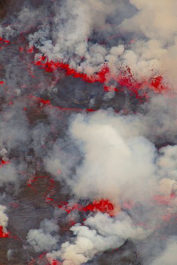 Red lava fountains and white plumes of gas alternate with dark areas of the thin, solid crust visible in between. (Photo: Tom Pfeiffer)