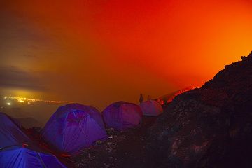 Our tents against the red sky and the lights of Goma town in the background. Two others are still awake, too, and visible as shadows behind the tents. (Photo: Tom Pfeiffer)