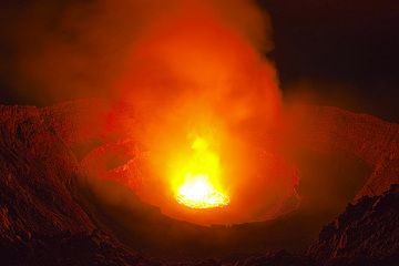 Vue grand angle (15 mm sur capteur 35 mm) de l'ensemble du cratère (caldeira) du Nyiragongo avec son lac de lave illuminant les parois intérieures la nuit. (Photo: Tom Pfeiffer)