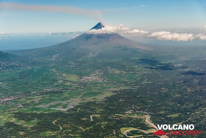 A light ash plume can be seen rising from the top of the volcano where the active vent of the 2018 eruption lies. The volcano forms a prominent landmark, rising to 2462 m elevation from near sea level out of the otherwise flat landscape of the Albay Gulf. (Photo: Tom Pfeiffer)