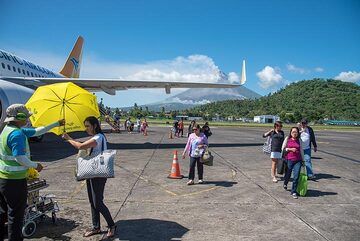 Landed safely in Legapzi! Umbrellas are handed to passengers for the short transit to the terminal: either to protect from heavy rain (as we experienced during departure later, or from the blazing sun). (Photo: Tom Pfeiffer)