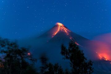 Shortly before dawn: misty clouds, the bluish light and the lava glow create a particular ambiance. (Photo: Tom Pfeiffer)