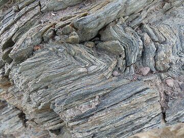 Les rochers qui affleurent dans la baie d'Athinios font partie d'une île beaucoup plus petite qui existait déjà avant l'activité du volcan. Ces vieilles roches ont été intensément plissées et métamorphisées. (Photo: Ingrid Smet)