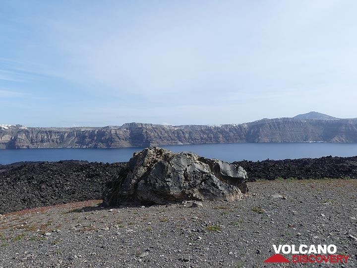Grosse bombe en croûte de pain sur Nea Kameni devant une coulée de lave en blocs gris foncé à noire. En arrière-plan se trouvent les falaises de la caldeira du centre de Théra et le mont Profitis Ilias (à droite). (Photo: Ingrid Smet)