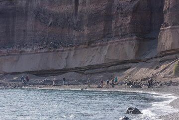 Bereits im Schatten des Nachmittags über den Strand laufen, mit der senkrechten Tuffsteinmauer im Hintergrund. (Photo: Tom Pfeiffer)