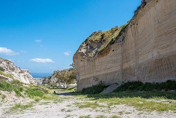 In diesem Bereich hat die Bimsstein-Falloutschicht aus den ersten Stunden der Eruption nahezu ihre maximale Mächtigkeit von ca. 7 Meter. Es liegt fast bis zum Boden frei (was bedeutet, dass sich der vorminoische Boden in diesem Bereich sehr dicht unter der Erde befindet). Esel als Maßstab; Die Fallout-Schicht ist das dunklere Band im unteren Drittel der Bimssteinwand. (Photo: Tom Pfeiffer)