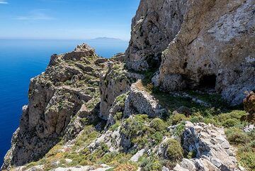 Über die alte Einsiedelei auf Mesa Vouno auf Santorini scheint wenig bekannt zu sein, obwohl es sich einst um einen großen Komplex mit vielen verschiedenen Baueinheiten gehandelt haben muss, die mindestens einer Reihe von Einsiedlern Schutz, Nahrung und Wasser boten. Es war über einen gepflasterten Weg mit der Stätte des antiken Thera auf dem Gipfel des Mesa Vouno verbunden und blieb wahrscheinlich viel länger bewohnt.
Mittlerweile sind nur noch wenige Ruinen erhalten, darunter eine ehemalige Küche in einer Höhle, mehrere überdachte Zellen zum Wohnen und eine Kapelle zum Beten. Es muss mehrere Felder gegeben haben, auf denen Gemüse angebaut wurde, und es gibt auch viele große Zisternen, die beide natürliche Höhlen nutzen und an der Seite der Felsen gebaut wurden. (Photo: Tom Pfeiffer)