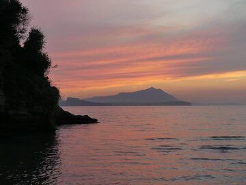 Rosa und orangefarbener Himmel über den Phlegräischen Inseln Procida (zentrale flache Silhouette mit Gebäude links) und Ischia (Silhouette im Hintergrund mit kleinem Berg rechts). (Photo: Ingrid Smet)