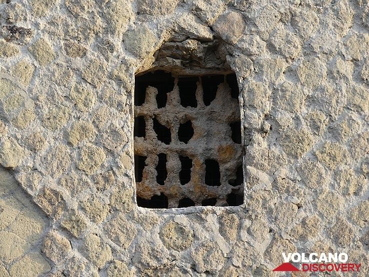 Whilst the wall of this building was constructed  with the yellow tuff that erupted from the Phlegraean fields some 15,000 years ago, the metal window grid got covered by ash and lapilli from the 79 AD eruption of Mt Vesuvius. (Photo: Ingrid Smet)