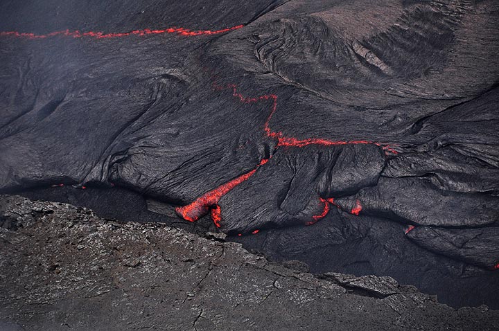Gros plan de la croûte noire refroidie au sommet d'une coulée de lave active sur le nouveau site d'éruption de fissure (Photo: Anastasia)