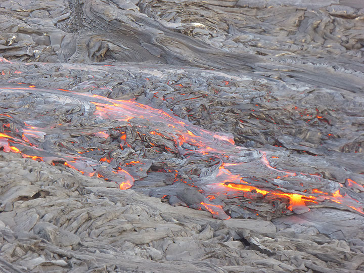 Zoom onto the fresh pahoehoe lava flows that are currently covering Erta Ale´s caldera floor. As the amount of overflows is so large, they can cool more slowly and hence their glowing hot interior can remain liquid for a number of days/weeks despite their quickly formed thin black crust. (Photo: Hans and Jooske)