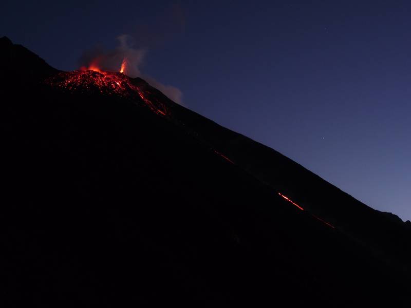 Top part of Stromboli's Sciara del Fuaocco. Droplets of lava illuminating and defining the NE vent right after an explosion, spattering from the NE hornito and glimpse of a thin lava flow from the overflowing/breached larger NE vent. 7 January 2013. (Photo: Ingrid)