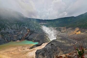 Kawah Ratu - Mont Tangkuban Perahu, Java Ouest, Indonésie

Le mont Tangkuban Perahu est le volcan le plus célèbre de Bandung, à seulement 28 km au nord de la ville. Ce volcan a une forme particulière, comme un bateau renversé (Tangkuban Perahu signifie en fait « bateau renversé »), il possède trois cratères dans lesquels les touristes peuvent traverser des zones. Ces trois cratères sont : Kawah Ratu, Kawah Domas et Kawah Upas.
Kawah Ratu, qui signifie « Cratère de la Reine », n'est aujourd'hui qu'un grand trou gris, qui possède parfois en son centre une mare d'eau. Des gaz toxiques s'accumulent parfois dans Kawah Ratu, ce qui rend la descente jusqu'au fond du cratère quelque peu risquée. Au-delà de la dépression en forme de selle de l'autre côté de Kawah Ratu se trouve le Kawah Upas, toujours actif, le plus ancien cratère de la montagne. Sur la falaise la plus à l'ouest, nous voyons un endroit où toute la végétation a été détruite par des vapeurs sulfureuses qui montent constamment. Sur les parois du cratère, notez les différentes couches de matériaux constitués de roches, de sable et de galets. Au fil du temps, de nouveaux cratères se sont formés encore et encore selon un déplacement plutôt constant d’ouest en est. (Photo: JessyEykendorp)