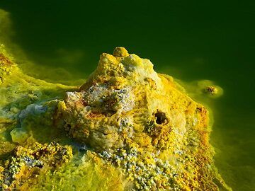 Yellow-white salt deposits at the edge of a green acid pond in Dallol (c)