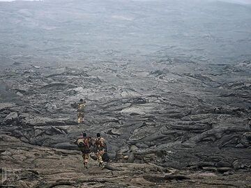 Ethiopian military and Afar policement escort walking across the vast lava flows in the summit caldera of Erta Ale (c)