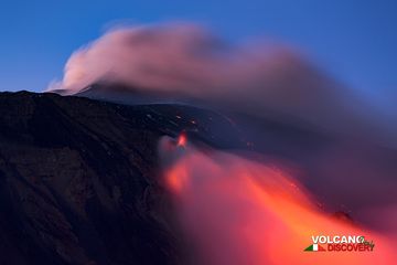 Вид на вершину в сумерках: выбросы пепла из жерл вершины и поток лавы из жерла нижней трещины. (Photo: Emanuela / VolcanoDiscovery Italia)