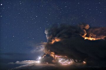 Clear starry night above the eruption of Eyafallajökull volcano (16 April 2010); lightnings within the eruption column illuminate part of the ash cloud. (Photo: marcofulle)