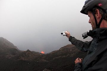 Finally, we're there! Despite the fog and light rain (still quite good conditions for Ambrym standards!), we can catch first glimpses of the boiling lava lake beneath the observation position. Pieter takes some photos. (Photo: Tom Pfeiffer)