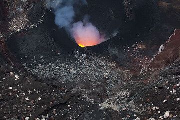 Bloques desgastados que han caído de las empinadas paredes interiores del cráter y una capa negra de lapilli recién expulsados y salpicaduras alrededor del respiradero. (Photo: Tom Pfeiffer)