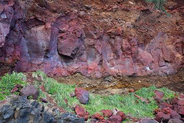 Un espectacular afloramiento geológico en el borde occidental de la caldera de Yasur expone un depósito rojo sólido de 3 a 4 metros de espesor que de hecho probablemente sea un depósito de un flujo piroclástico rico en salpicaduras, tan bien soldado  (Photo: Tom Pfeiffer)