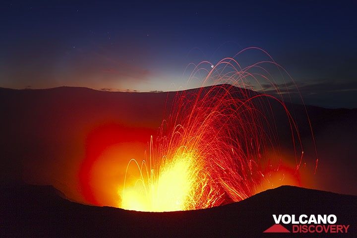 A stronger eruption after sunset sends glowing bombs into the sky, hitting the moon. (Photo: Tom Pfeiffer)