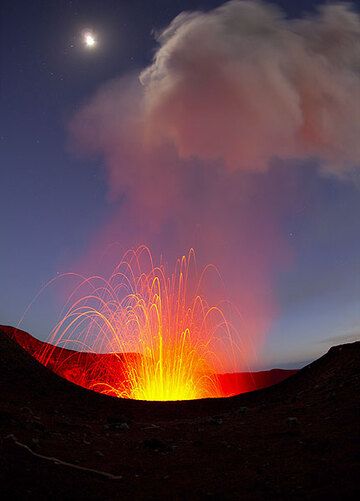 A bright moon illuminates the sky behind the fireworks of Yasur volcano (Photo: Tom Pfeiffer)