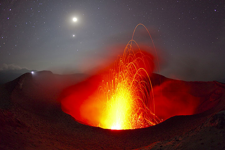 Извержения кратера Yasur вулкана под луной и звездным небом. Факел далекой наблюдателя на противоположный край выглядит как второй Луны. (Photo: Tom Pfeiffer)