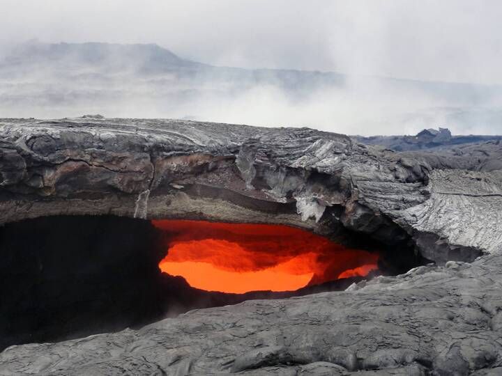 A skylight reveals the fluid lava stream within the main tube on the June 27 lava flow. The recently active perched lava pond is in the upper left portion of the photograph.