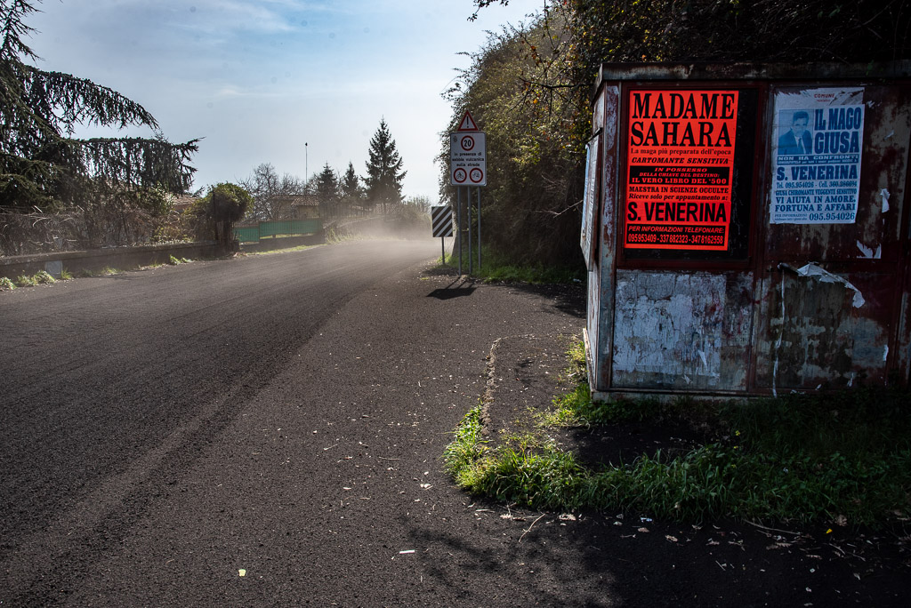 Ash-covered street and ads from local magicians ready to help (image: Tom Pfeiffer / VolcanoDiscovery)