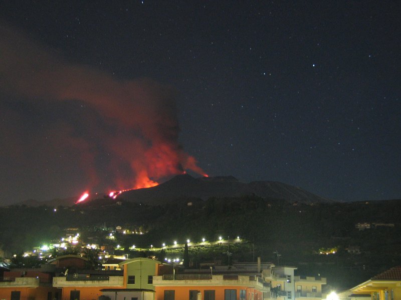 Etna's lava flows descending into Valle del Bove; strombolian activity from the New SE cone (c) and strong glow from Voragine summit crater (r) (image: Osservatorio Meteorologico Nunziata webcam, view from E)