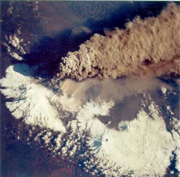NASA photo of the eruption of Klyuchevsky volcano on 30 September, 1994, the volcano's largest explosion in 40 years. The large eruption cloud billowed from the summit, and deposited volcanic ash (pulverized rock) on the snow-covered region to the east. Another small steam plume was rising from Bezymianny, the smaller “C”-shaped volcanic summit south of Klyuchevskaya.